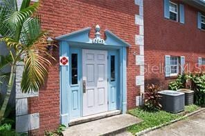 doorway to property with brick siding and cooling unit