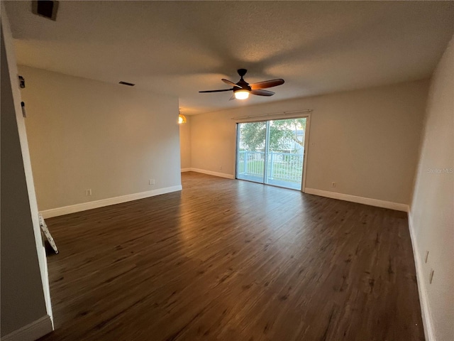 empty room featuring a ceiling fan, dark wood-style flooring, and baseboards