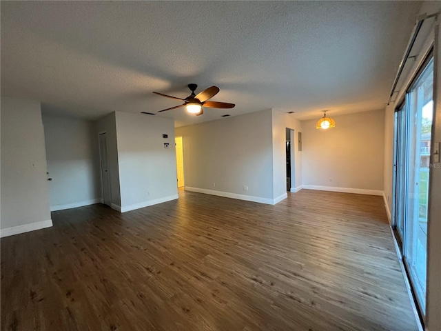 empty room featuring a textured ceiling, a ceiling fan, dark wood-style flooring, and baseboards