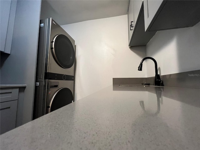 washroom featuring stacked washer and clothes dryer and a sink
