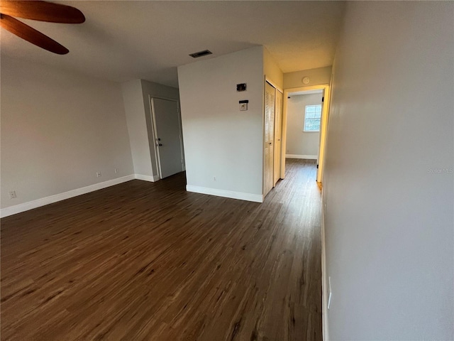 spare room with ceiling fan, dark wood finished floors, and baseboards