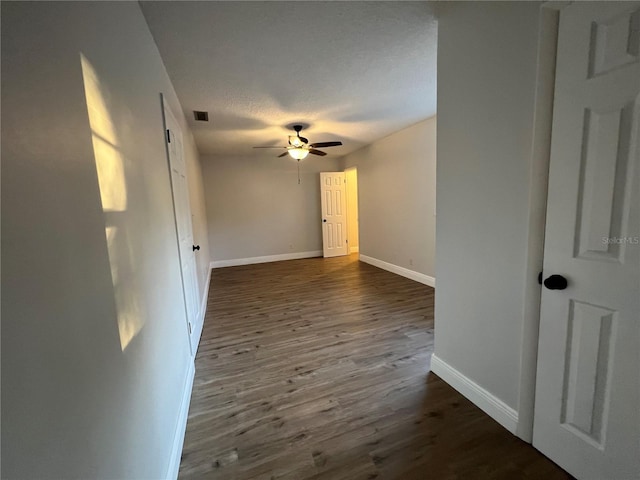 unfurnished room featuring a textured ceiling, ceiling fan, and dark hardwood / wood-style flooring