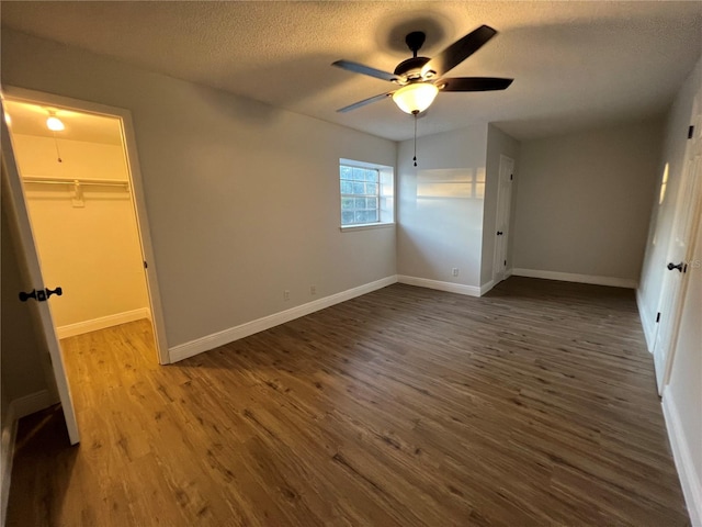 unfurnished bedroom featuring ceiling fan, a textured ceiling, a spacious closet, hardwood / wood-style flooring, and a closet