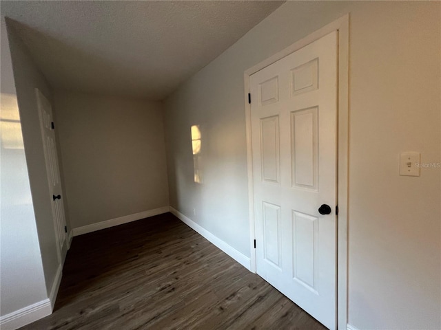hall with dark wood finished floors, baseboards, and a textured ceiling