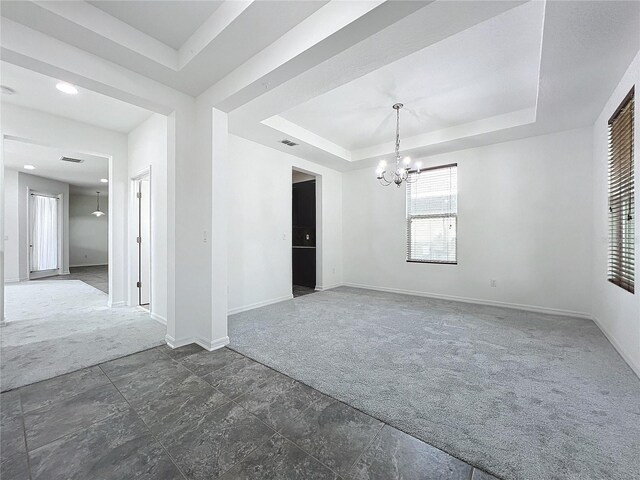 carpeted empty room with a chandelier and a tray ceiling