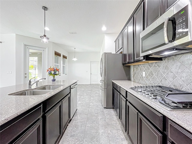 kitchen with sink, hanging light fixtures, stainless steel appliances, backsplash, and light tile patterned floors