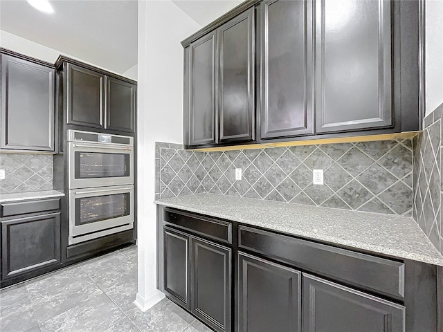 kitchen featuring stainless steel double oven, light tile patterned floors, and tasteful backsplash