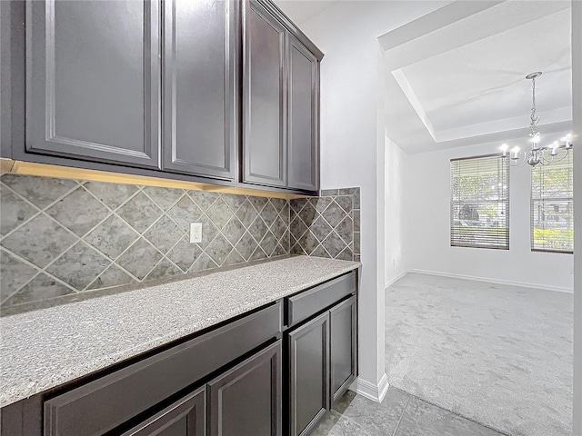 kitchen with backsplash, an inviting chandelier, decorative light fixtures, light colored carpet, and dark brown cabinetry