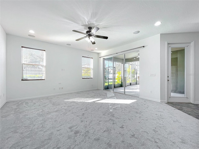 carpeted spare room with ceiling fan, a healthy amount of sunlight, and a textured ceiling