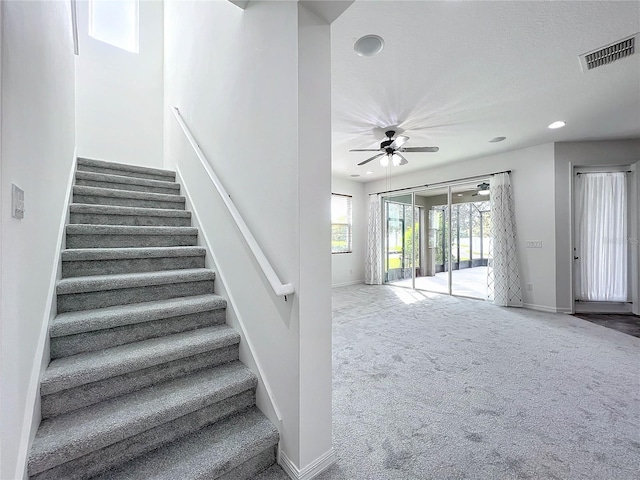 stairs featuring carpet flooring and ceiling fan