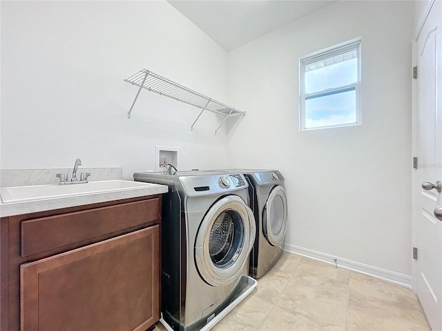 clothes washing area with separate washer and dryer, sink, and cabinets