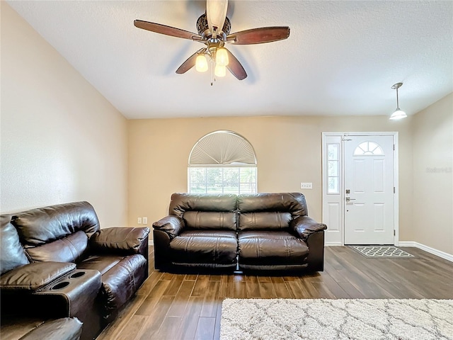 living room with a textured ceiling, wood-type flooring, and ceiling fan