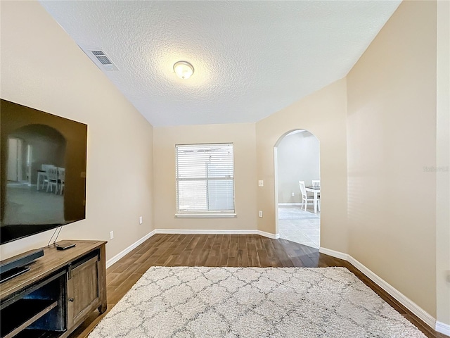 interior space featuring a textured ceiling, vaulted ceiling, and dark hardwood / wood-style floors