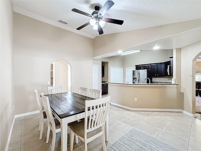 tiled dining area featuring lofted ceiling, a textured ceiling, and ceiling fan