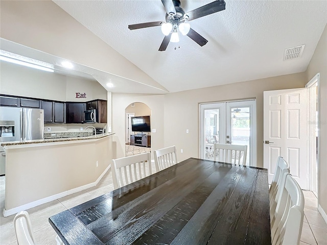 unfurnished dining area featuring sink, light tile patterned floors, a textured ceiling, and lofted ceiling