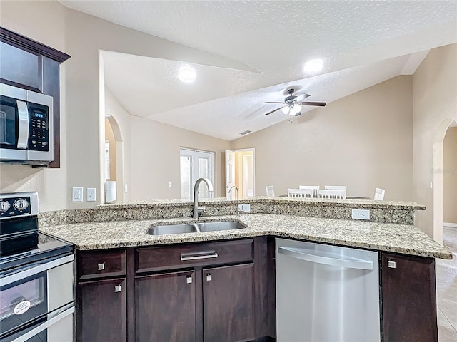 kitchen with sink, a textured ceiling, kitchen peninsula, stainless steel appliances, and lofted ceiling