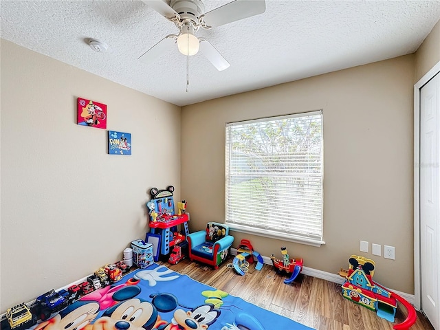 game room featuring a textured ceiling, hardwood / wood-style flooring, and ceiling fan