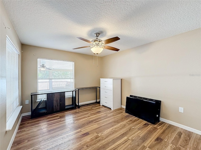 interior space with a textured ceiling, wood-type flooring, and ceiling fan