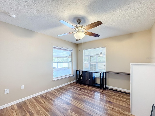 empty room featuring dark wood-type flooring, a textured ceiling, and ceiling fan