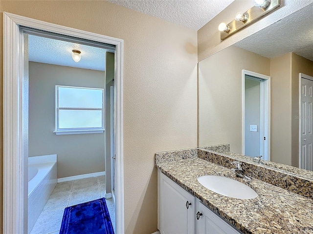 bathroom featuring vanity, a relaxing tiled tub, a textured ceiling, and tile patterned flooring