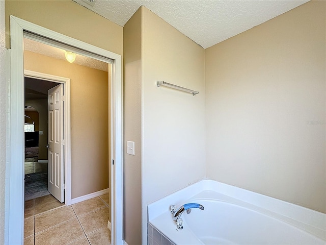 bathroom with a tub, a textured ceiling, and tile patterned floors