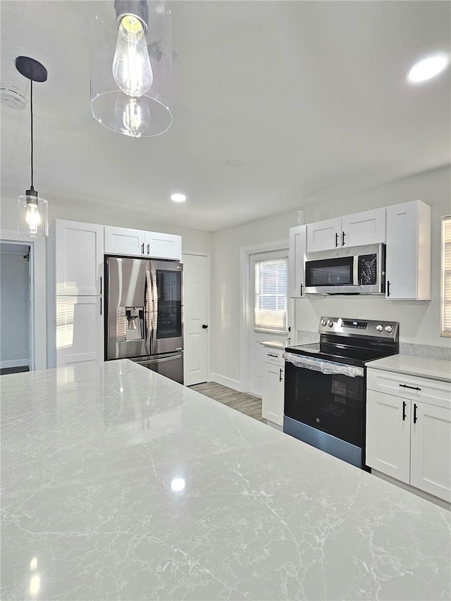 kitchen featuring light stone countertops, hanging light fixtures, white cabinets, and stainless steel appliances