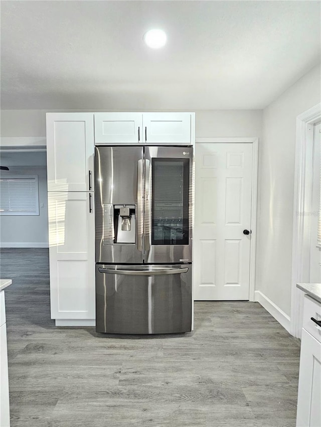 kitchen with white cabinets, stainless steel fridge, and light wood-type flooring