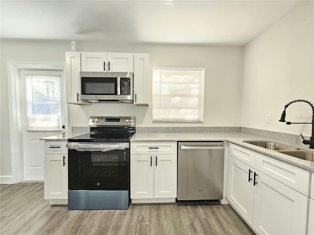 kitchen featuring white cabinetry, sink, stainless steel appliances, and light hardwood / wood-style floors