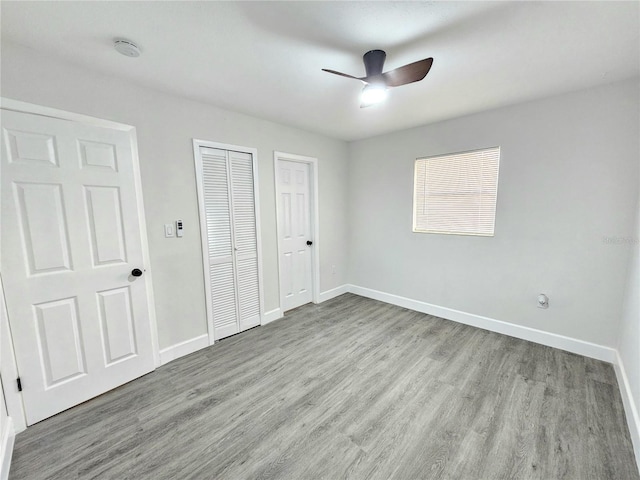 unfurnished bedroom with multiple closets, ceiling fan, and light wood-type flooring