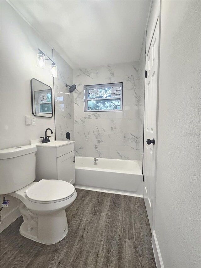 full bathroom with vanity, tiled shower / bath combo, hardwood / wood-style flooring, and toilet