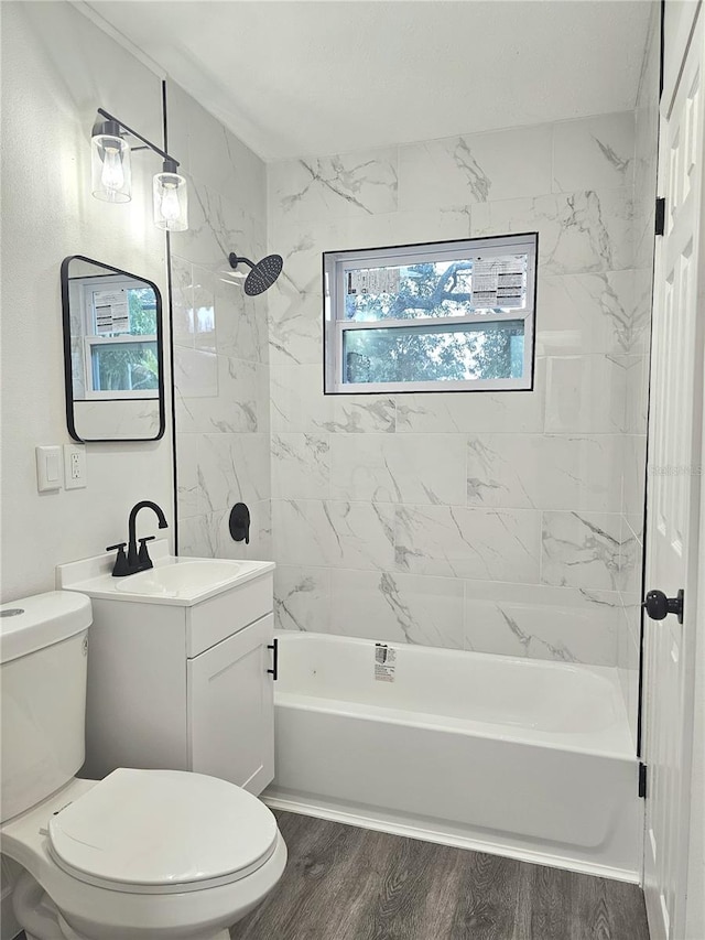 full bathroom with a wealth of natural light, hardwood / wood-style flooring, toilet, and tiled shower / bath