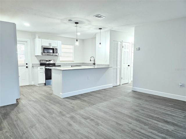 kitchen featuring white cabinetry, sink, kitchen peninsula, decorative light fixtures, and appliances with stainless steel finishes