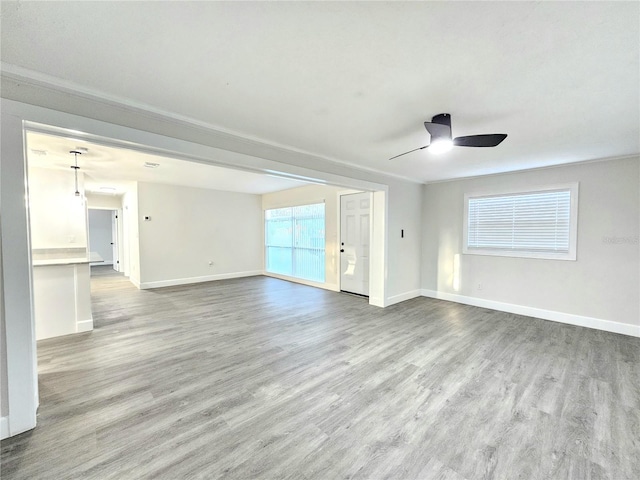 unfurnished living room with light hardwood / wood-style floors, ceiling fan, and ornamental molding