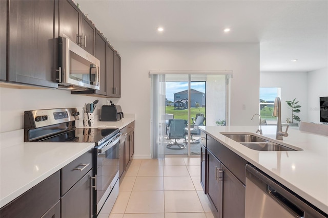 kitchen with light tile patterned floors, a healthy amount of sunlight, appliances with stainless steel finishes, and sink