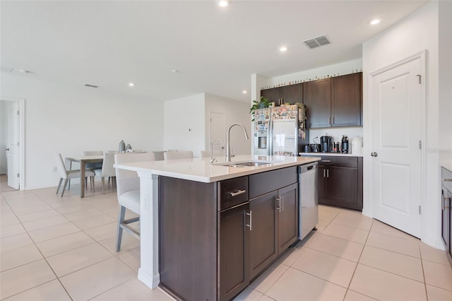 kitchen with dishwasher, a kitchen island with sink, white fridge with ice dispenser, sink, and dark brown cabinetry