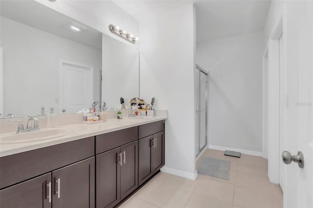 bathroom with a shower with door, tile patterned flooring, and vanity