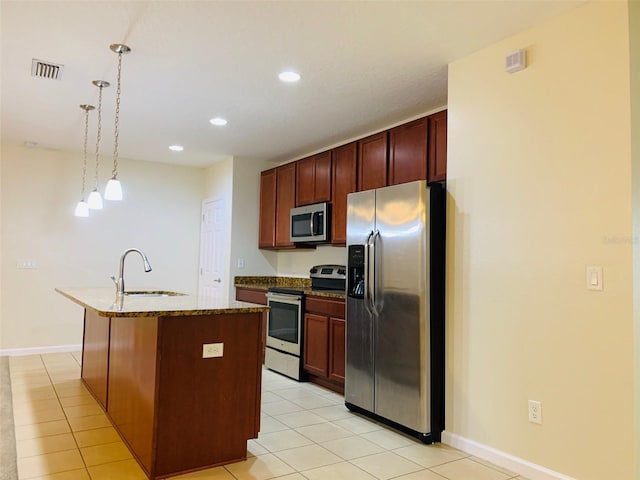 kitchen with sink, light tile patterned floors, an island with sink, appliances with stainless steel finishes, and decorative light fixtures