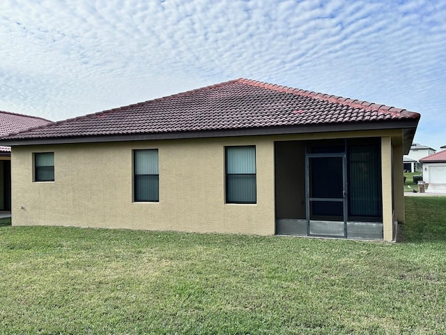 rear view of property featuring a sunroom and a lawn