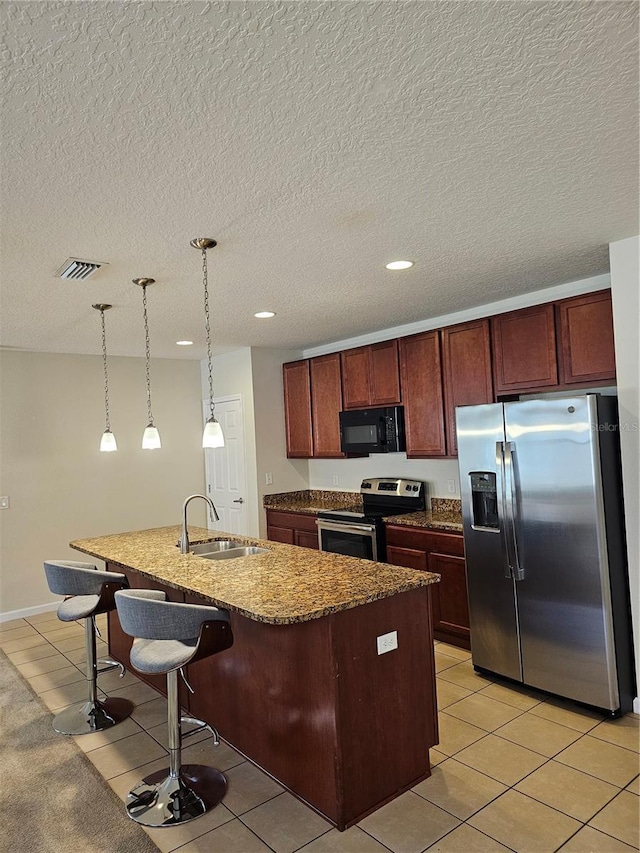 kitchen with light tile patterned flooring, an island with sink, stainless steel appliances, and sink