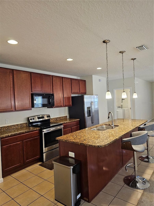 kitchen featuring stainless steel appliances, sink, separate washer and dryer, a center island with sink, and a breakfast bar area