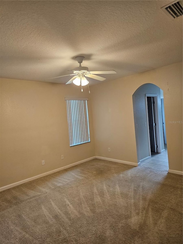 spare room with light carpet, ceiling fan, and a textured ceiling