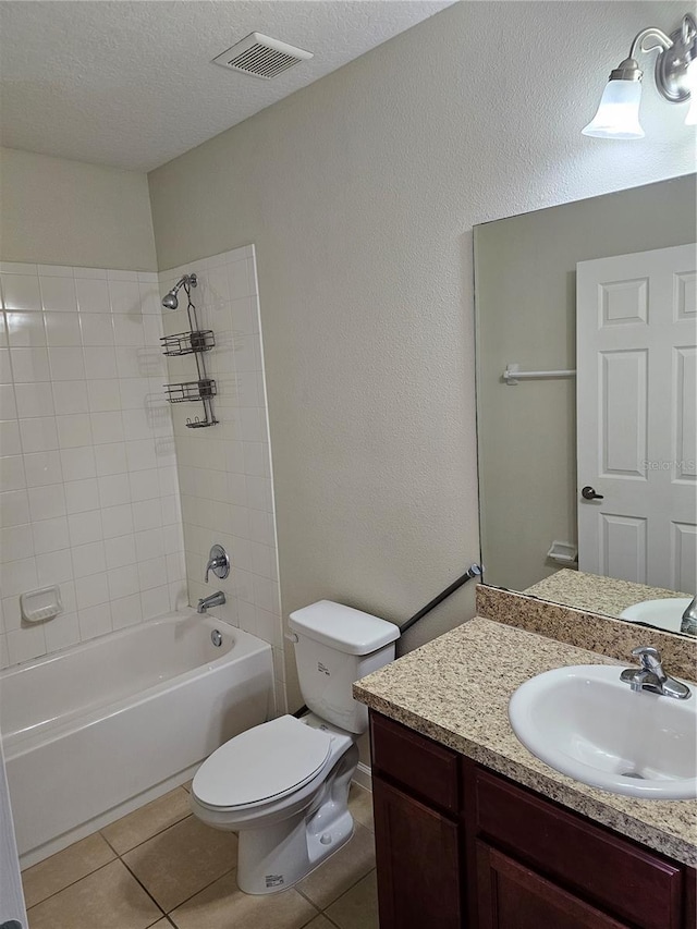 full bathroom with vanity, tile patterned flooring, tiled shower / bath combo, toilet, and a textured ceiling