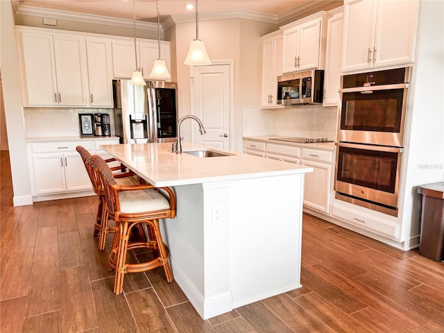 kitchen featuring a kitchen island with sink, hanging light fixtures, stainless steel appliances, hardwood / wood-style floors, and sink