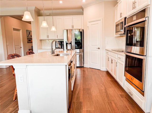 kitchen with stainless steel appliances, a kitchen island with sink, sink, and white cabinets