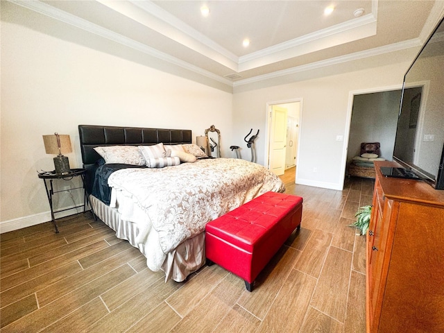 bedroom with crown molding, hardwood / wood-style flooring, and a tray ceiling