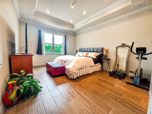 bedroom with ornamental molding, hardwood / wood-style floors, and a tray ceiling