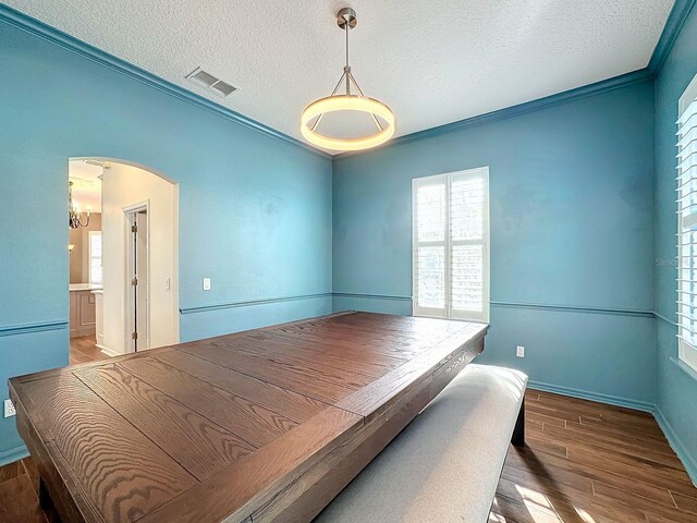 bedroom with ornamental molding, hardwood / wood-style floors, and a textured ceiling