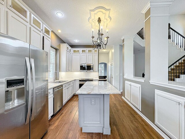 kitchen featuring hardwood / wood-style floors, white cabinets, stainless steel appliances, pendant lighting, and a center island