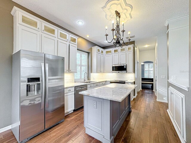 kitchen with a center island, appliances with stainless steel finishes, pendant lighting, and a healthy amount of sunlight