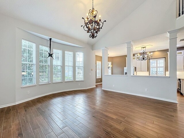 unfurnished living room with ornate columns, a notable chandelier, a textured ceiling, and dark hardwood / wood-style floors